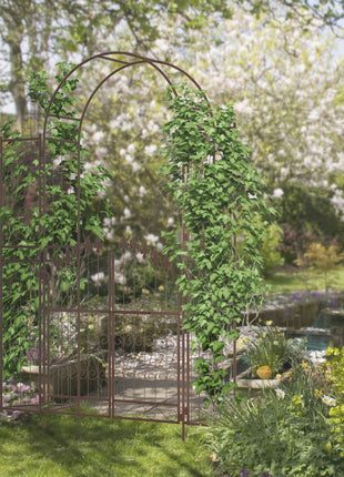 7' Metal Garden Arbor, Garden Arch with Gate, Fleur De Lis Motif, Latching Doors, Planter Shelves for Climbing Vines, Ceremony, Weddings, Party, Garden, Backyard, Lawn, Brown